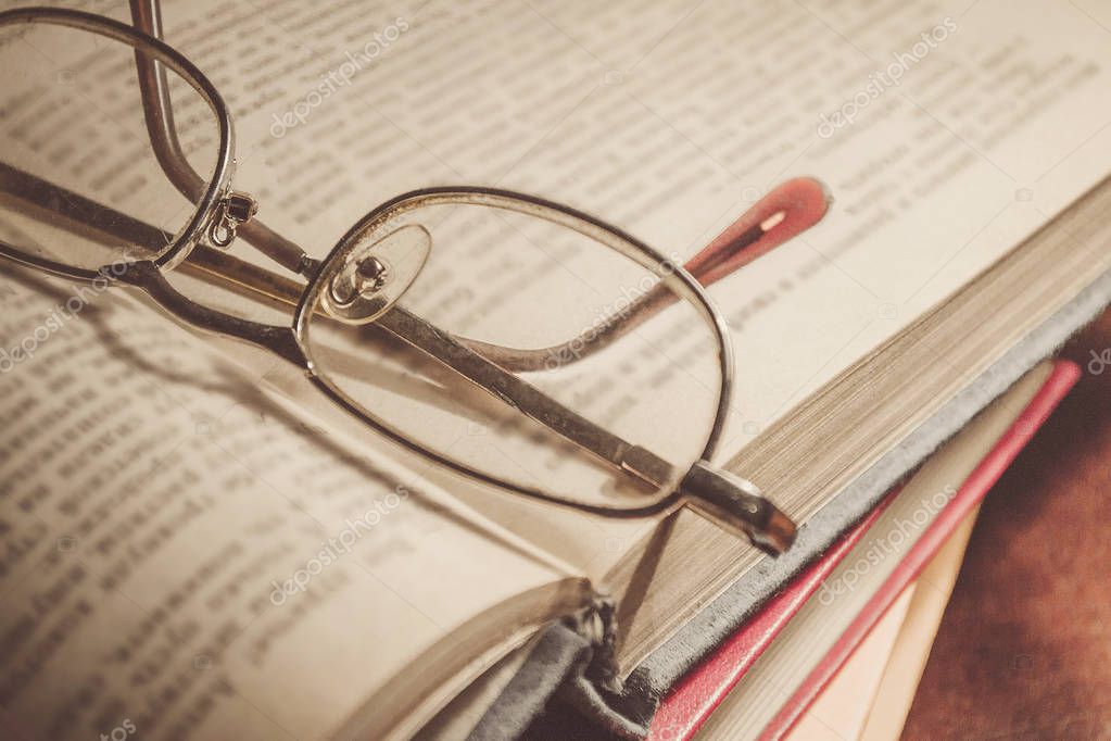 Glasses on the book. A stack of books with colorful covers. The library