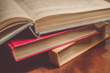 Renkli kapaklı kitap yığını. Kitaplık veya kitapçı. Kitap veya ders kitapları. Ön planda açık kitap.