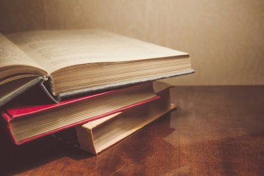 Renkli kapaklı kitap yığını. Kitaplık veya kitapçı. Kitap veya ders kitapları. Ön planda açık kitap.