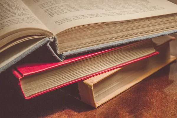 Renkli kapaklı kitap yığını. Kitaplık veya kitapçı. Kitap veya ders kitapları. Ön planda açık kitap.