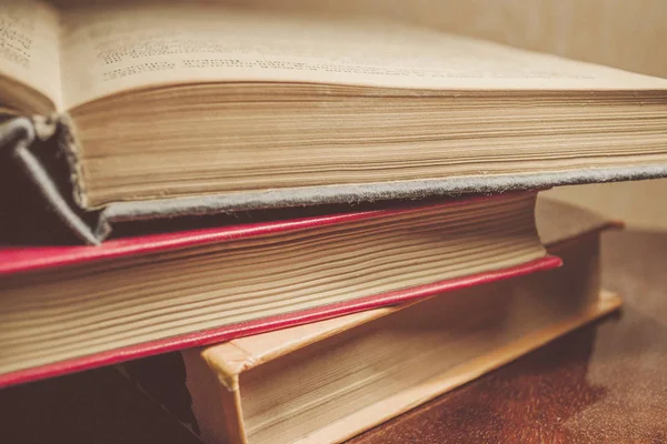 Renkli kapaklı kitap yığını. Kitaplık veya kitapçı. Kitap veya ders kitapları. Ön planda açık kitap.