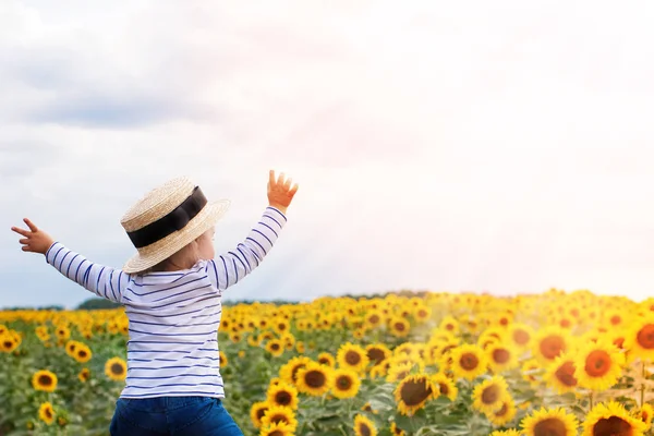 Meisje permanent in zonnebloemen veld — Stockfoto