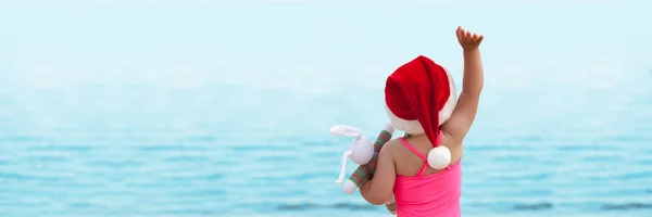 Menina olhando para o mar em chapéu de Santa — Fotografia de Stock