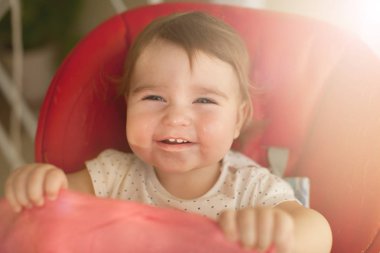 Kırmızı sandalyesi oturan bebek kız