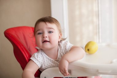 Mama sandalyesi ile elma içinde oturan bebek kız