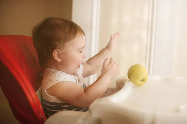 Κορίτσι βρέφος κάθεται σε καρεκλάκι με μήλο — Φωτογραφία Αρχείου