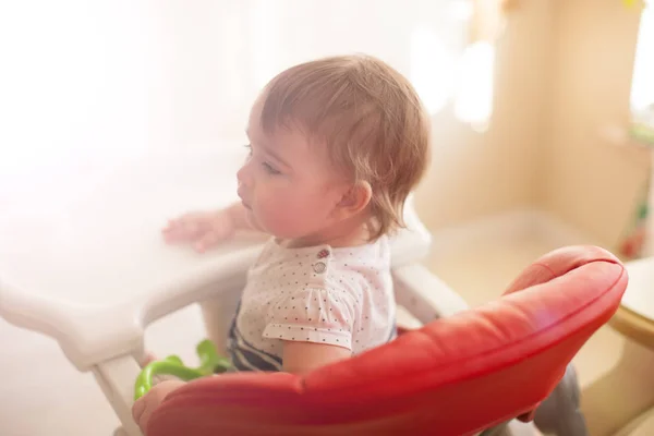 Kırmızı sandalyesi oturan bebek kız