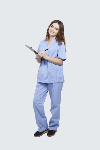 Doctor standing and holding clipboard — Stock Photo, Image