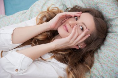 Kadın yatakta yatarken ve yüz elleriyle dokunuyor