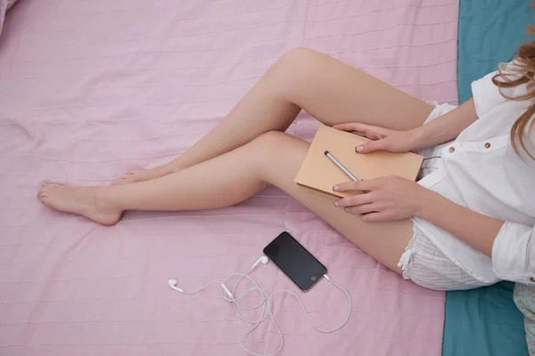 Mujer sentada en la cama sosteniendo el cuaderno — Foto de Stock