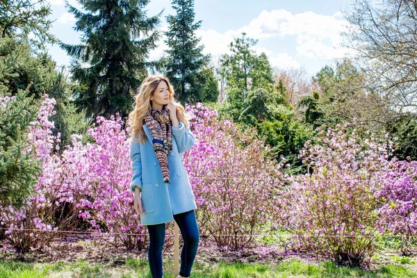 Woman standing in front of bushes with flowers — Stock Photo, Image