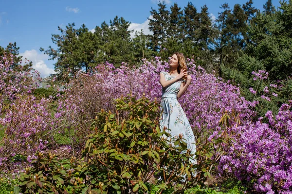 Nő áll a lila virágok, bokrok — Stock Fotó