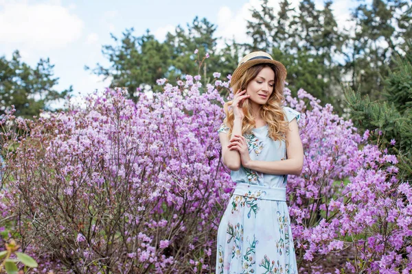 Kvinna som står framför violetta blommor — Stockfoto