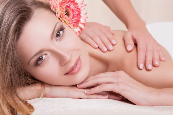 Mulher deitada na mesa de massagem com flor — Fotografia de Stock