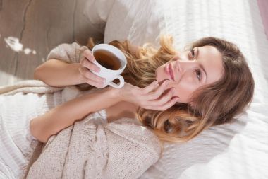 Bardak çay ile yatakta yatarken kadın