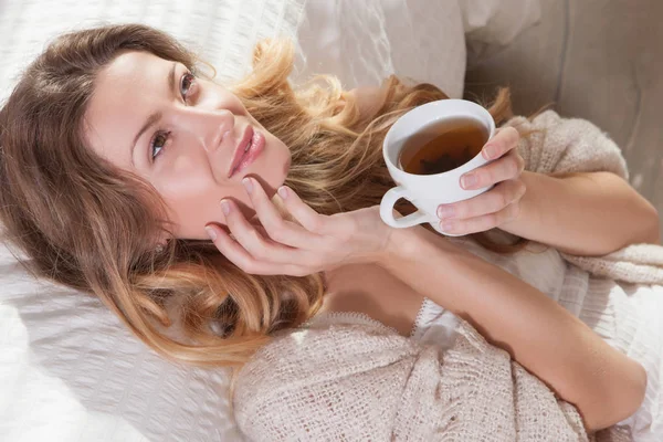 Bardak çay ile yatakta yatarken kadın