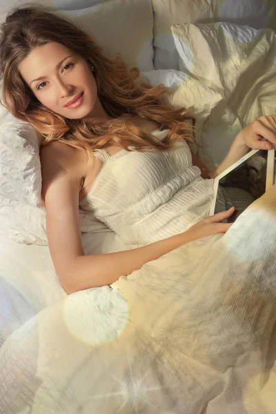 Femme couchée au lit et tenant la tablette — Photo