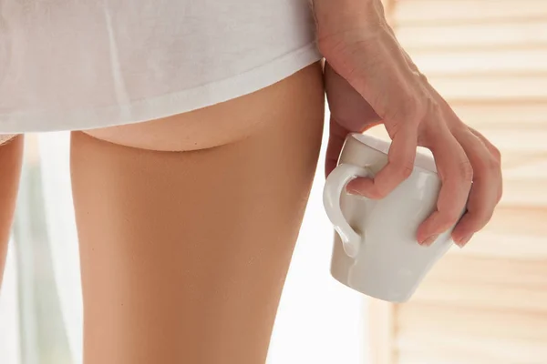 Woman legs and hand with cup — Stock Photo, Image
