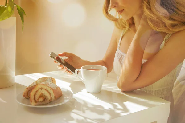 Mujer mirando smartphone durante el desayuno — Foto de Stock