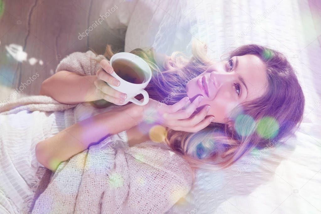Woman lying on bed with cup of tea
