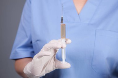 Doktor elinde şırınga tutuyor.