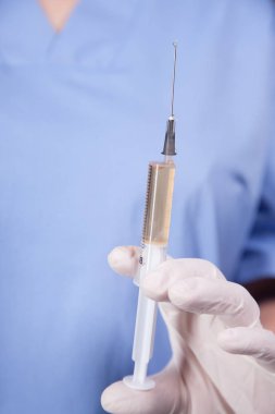 Doktor elinde şırınga tutuyor.