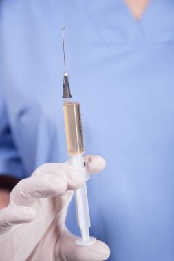 Doktor elinde şırınga tutuyor.