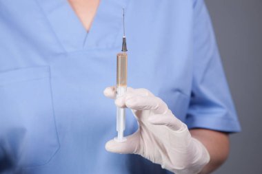 Doktor elinde şırınga tutuyor.