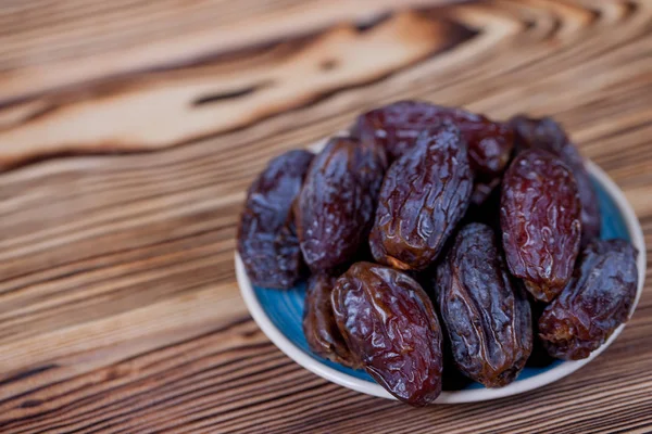 Traditional Arabian food. Pile of tasty dates with walnuts on wooden table background.