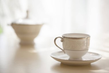 Beyaz kahve fincanı ile plaka ayakta masada, closeup bulanık arka plan