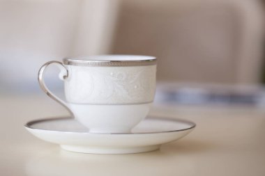 Beyaz kahve fincanı ile plaka ayakta masada, closeup bulanık arka plan