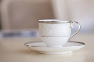 Beyaz kahve fincanı ile plaka ayakta masada, closeup bulanık arka plan