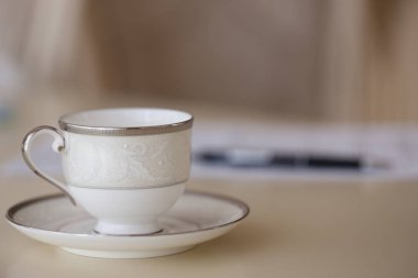 Beyaz kahve fincanı ile plaka ayakta masada, closeup bulanık arka plan