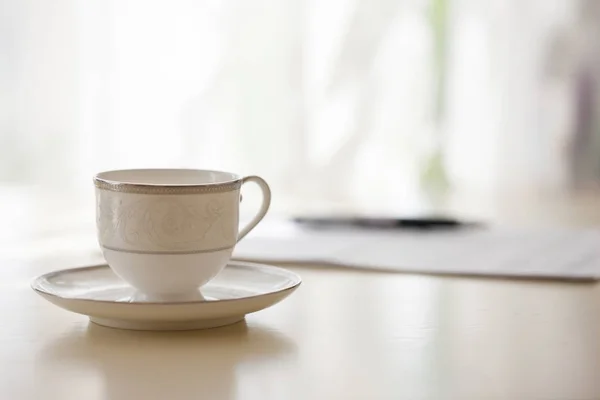 Beyaz kahve fincanı plaka ayakta belge ve kalem, tablo ile closeup bulanık arka plan