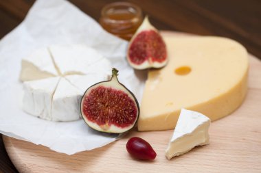 Dilimlenmiş peynir ve ahşap masa üzerinde incir çeşitleri closeup. Gıda arka plan, lezzetli yemek seti 