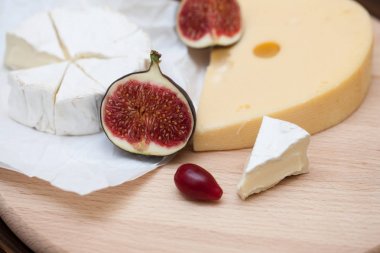 Dilimlenmiş peynir ve ahşap masa üzerinde incir çeşitleri closeup. Gıda arka plan, lezzetli yemek seti 