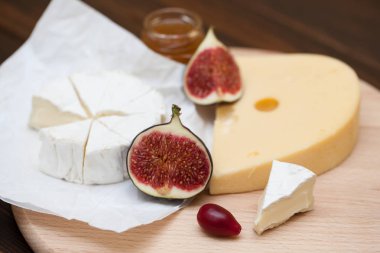 Dilimlenmiş peynir ve ahşap masa üzerinde incir çeşitleri closeup. Gıda arka plan, lezzetli yemek seti 