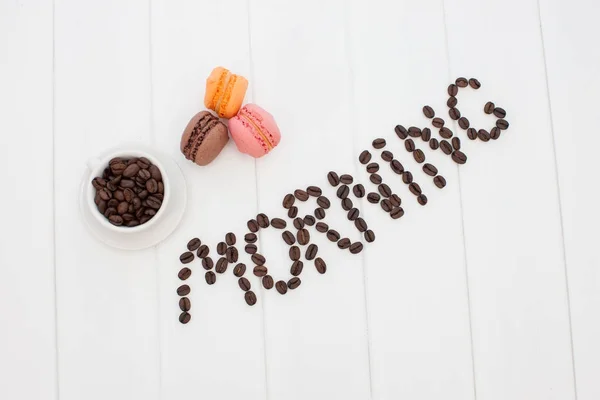 Morning coffee concept. Word coffee made of fried coffee beans on white wooden table background.