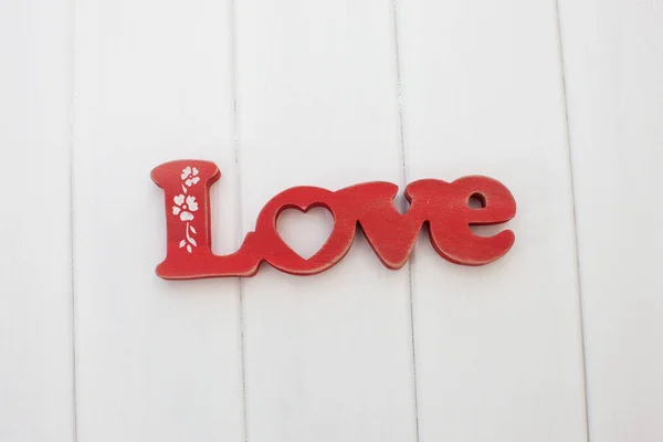 Red wooden letters love on white wooden planks background