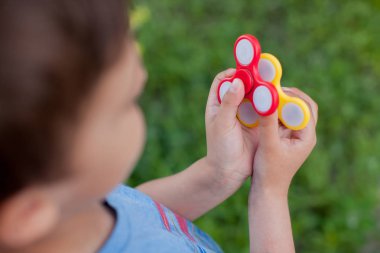 Çocuk yeni oyuncaklar ile oynama. Yaz parkta duran ve kırmızı ve sarı spinners elinde tutan çocuk çocuk closeup