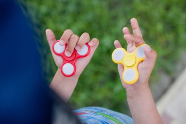 Çocuk yeni oyuncaklar ile oynama. Yaz parkta duran ve kırmızı ve sarı spinners elinde tutan çocuk çocuk closeup