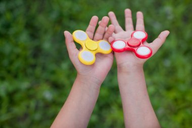 Çocuk yeni oyuncaklar ile oynama. Yaz parkta duran ve kırmızı ve sarı spinners elinde tutan çocuk çocuk closeup