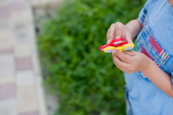 男孩玩新玩具 男孩的特写在夏天公园站立和藏品红色和黄色纺纱在手 — 图库照片