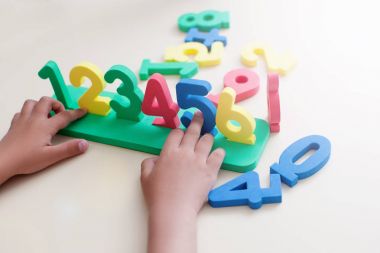 Çocuk çocuk elleri beyaz masa arka plan üzerinde renkli sayılarla oynamak portre çekim