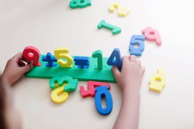 Çocuk çocuk elleri beyaz masa arka plan üzerinde renkli sayılarla oynamak portre çekim