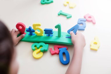 Çocuk çocuk elleri beyaz masa arka plan üzerinde renkli sayılarla oynamak portre çekim