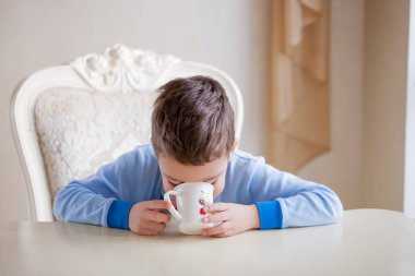 Güzel çocuk çocuk Kupası, eve iç arka plan ile yetişkin masada oturan closeup