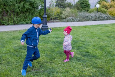 Mutlu çocuklar yeşil çimenlerin üzerinde oyun. Ve genç erkek kardeşim dışarıda eğleniyor
