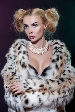 Dalgalı saçlı güzel sarışın kadın degrade arka plan üzerinde duran lüks kürk palto giyiyor Studio portresi