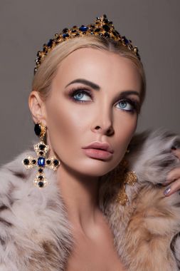 Lüks elbise, kürk manto, şık küpe ve taç giyen güzellik kadın portre stüdyo çekim